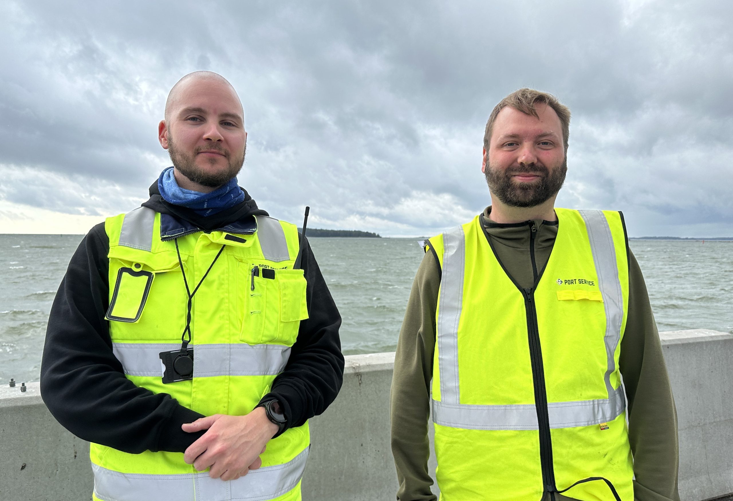 Kuvassa ovat kaksi SF Port Servicen kenttävastaava. Heillä on turvaliivit päällä. Takana näkyy meri.